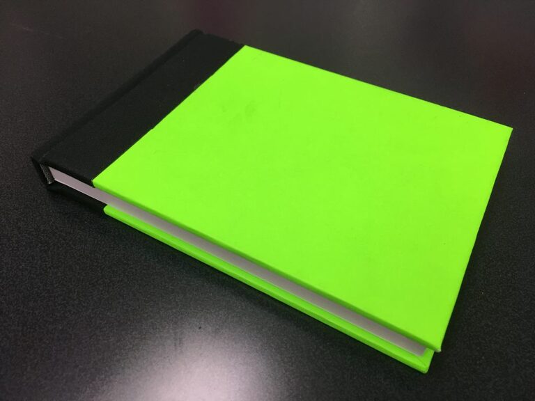                                                         明るい緑色に黒色で背継ぎ表紙を施された本                                                        